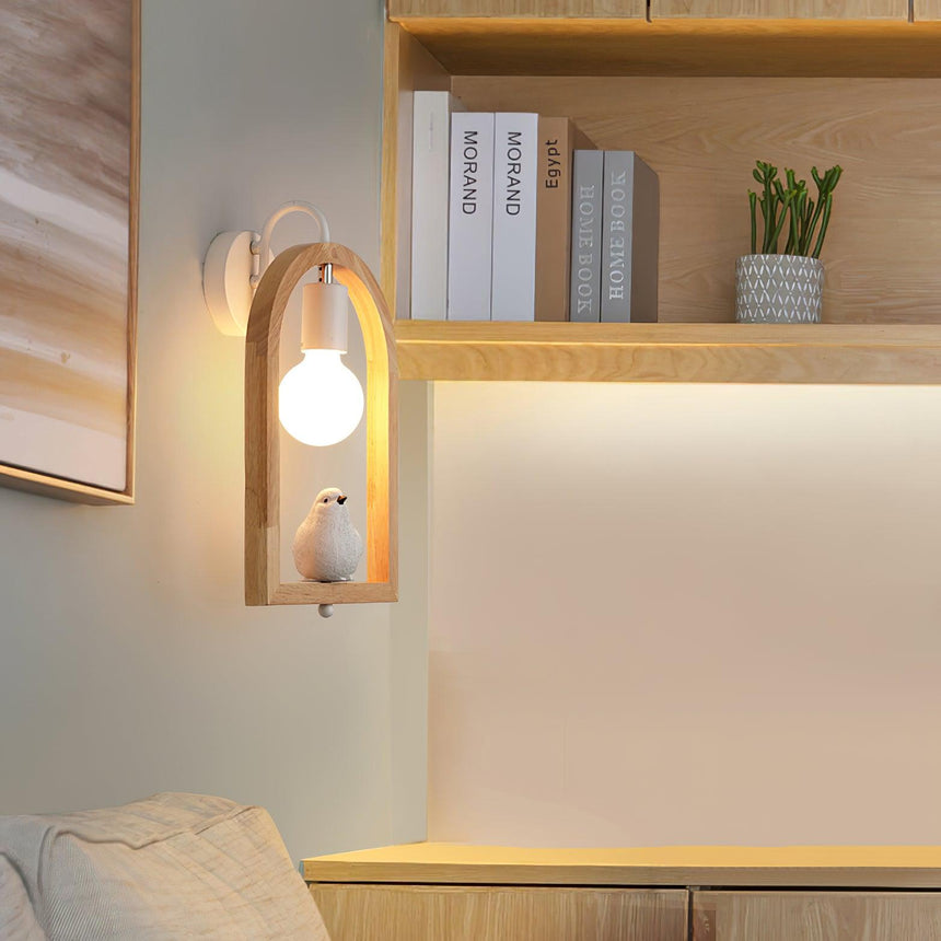 Sconce lit beside shelving with books and a plant above a pale bench