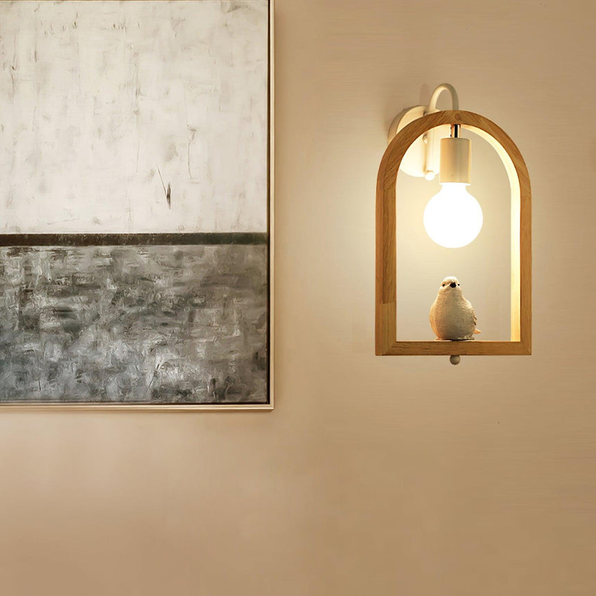 Sconce lit beside framed artwork leaning against a warm beige wall