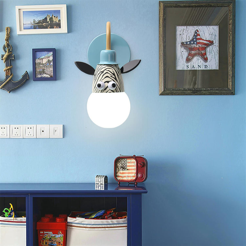 The zebra lamp lit on a blue wall above a low shelf and framed prints