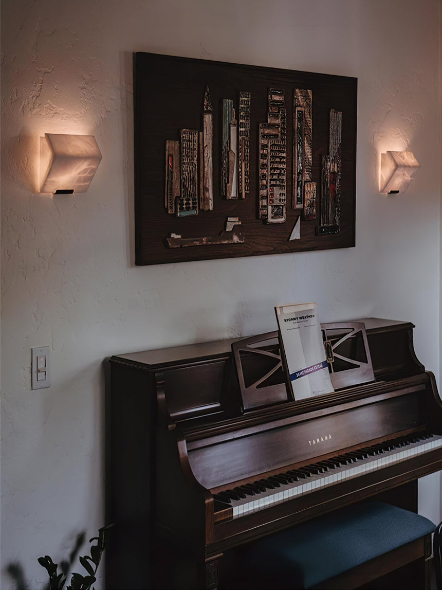 A pair of single blocks lit on either side of a large print above a piano