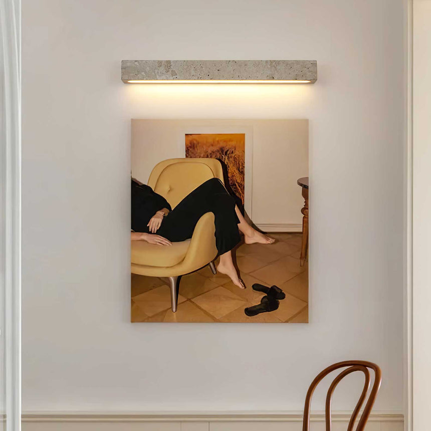Travertine bar lit above a framed painting beside a bentwood chair