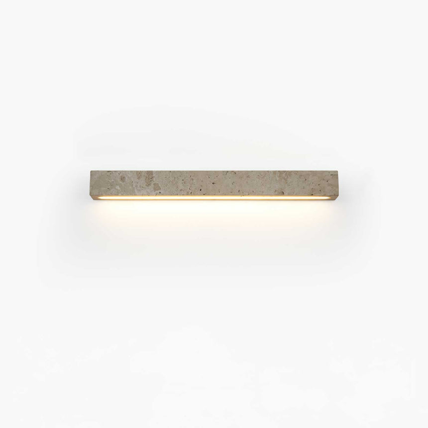 The shorter bar lit on a pale wall, the light pooling softly under the stone