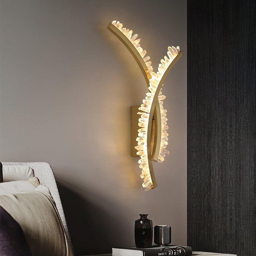 The crossed arms lit above a nightstand with vases beside a bed