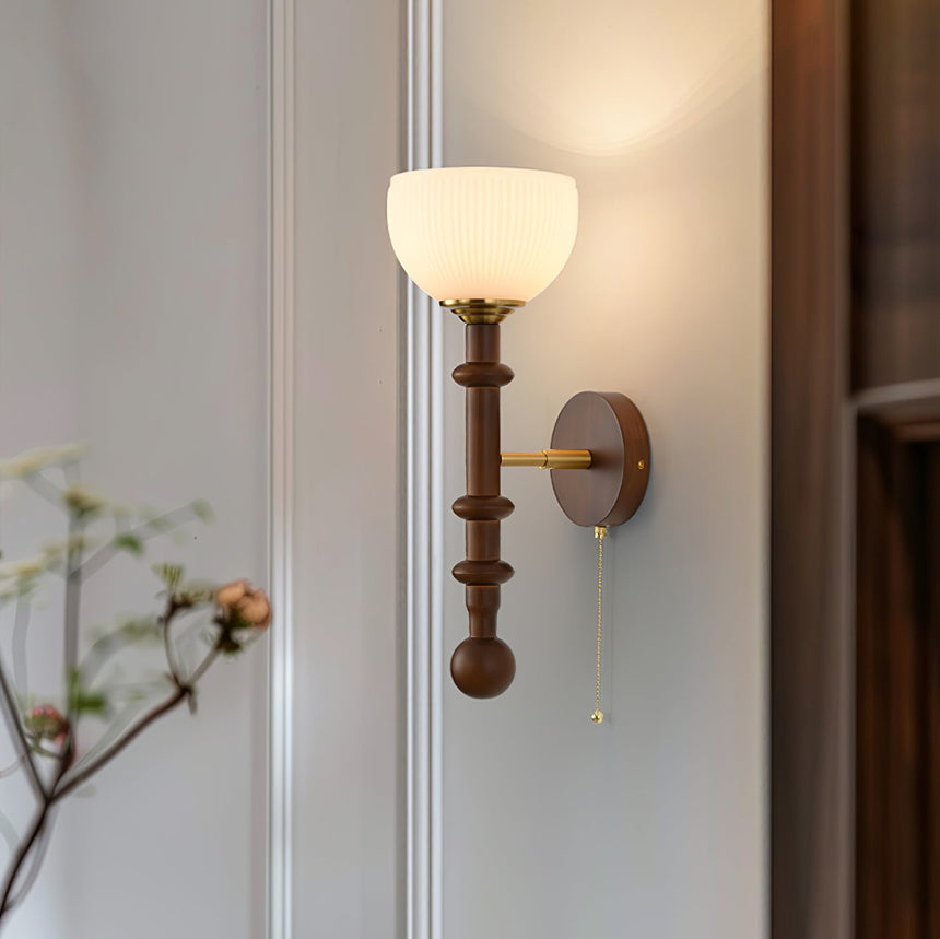 Close view of the turned walnut column with its brass rings and pull chain