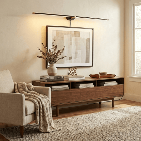 Slim rod lit above a framed print over a long walnut console with books and a vase
