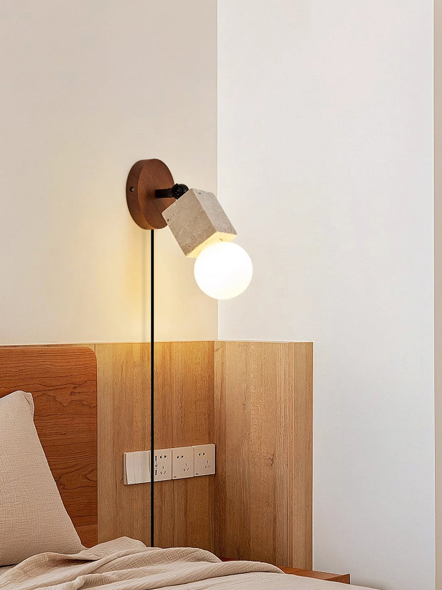 Sconce lit beside a bed with a wood headboard, the cord running down the wall
