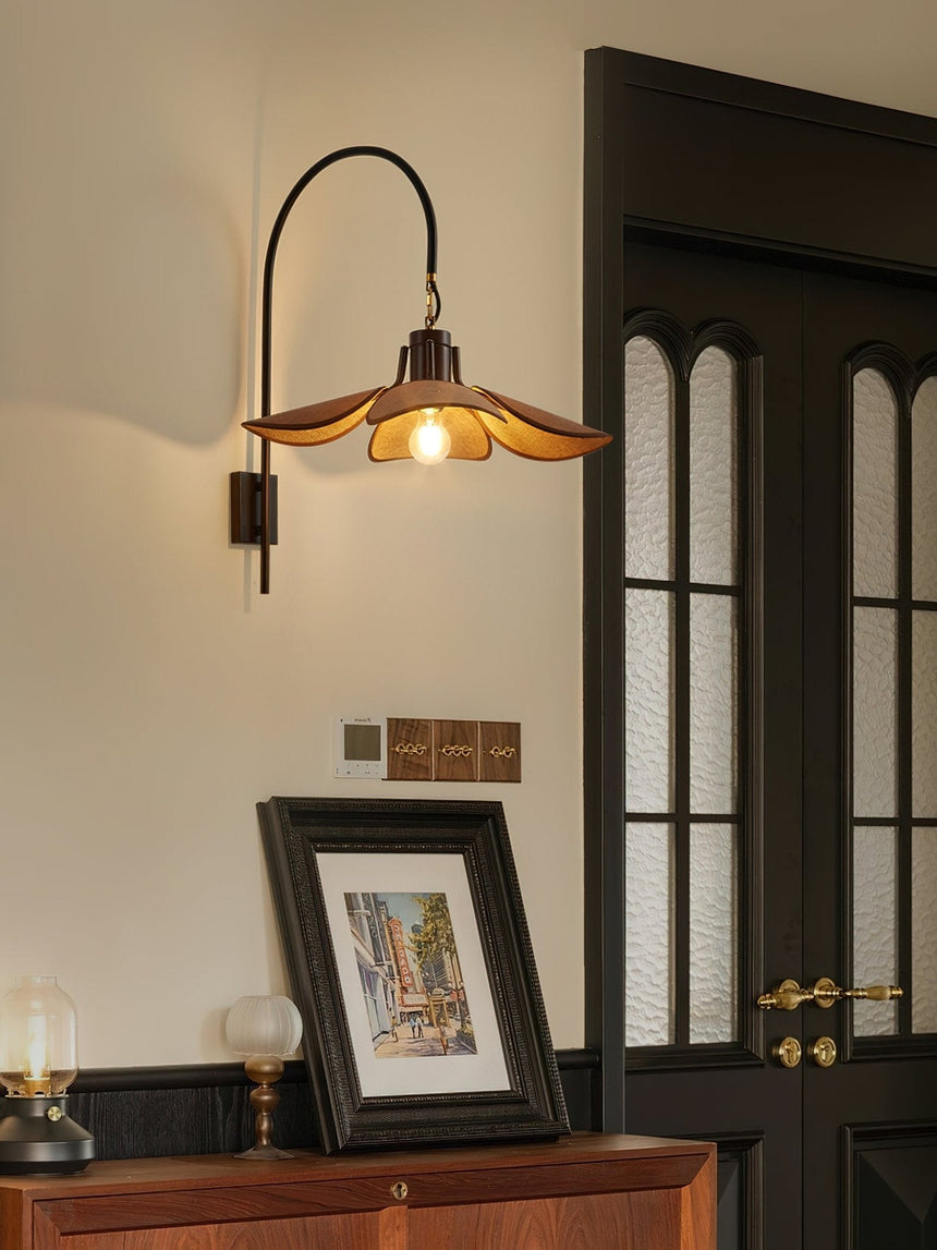 Sconce lit beside a dark door above a sideboard with a framed print