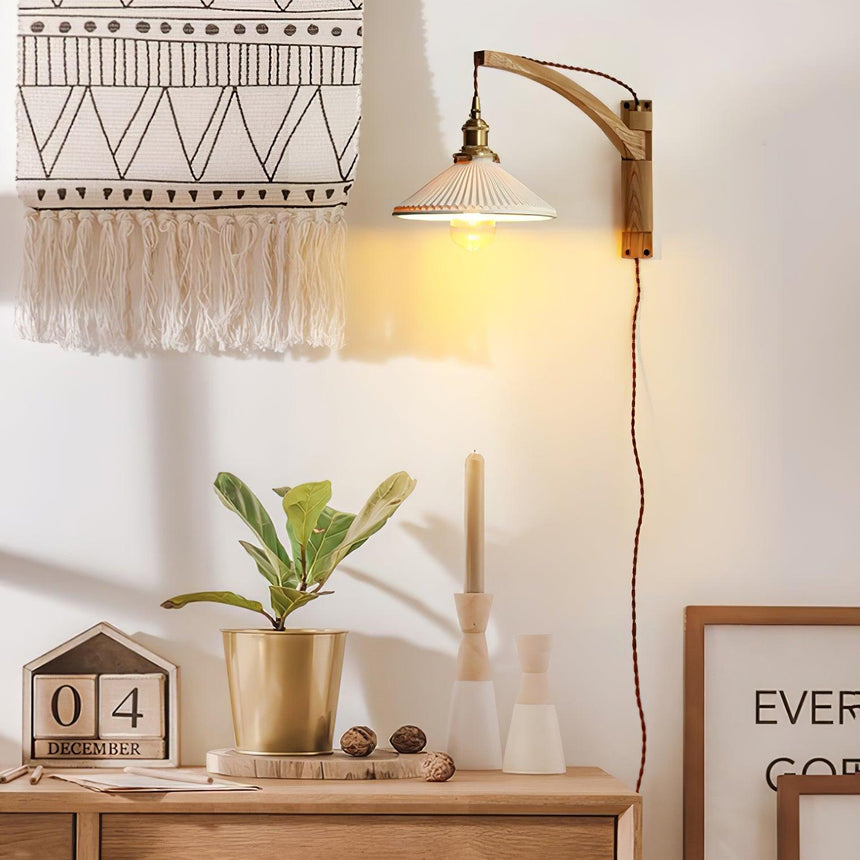 The curved arm version above a dresser with a plant and a woven wall hanging