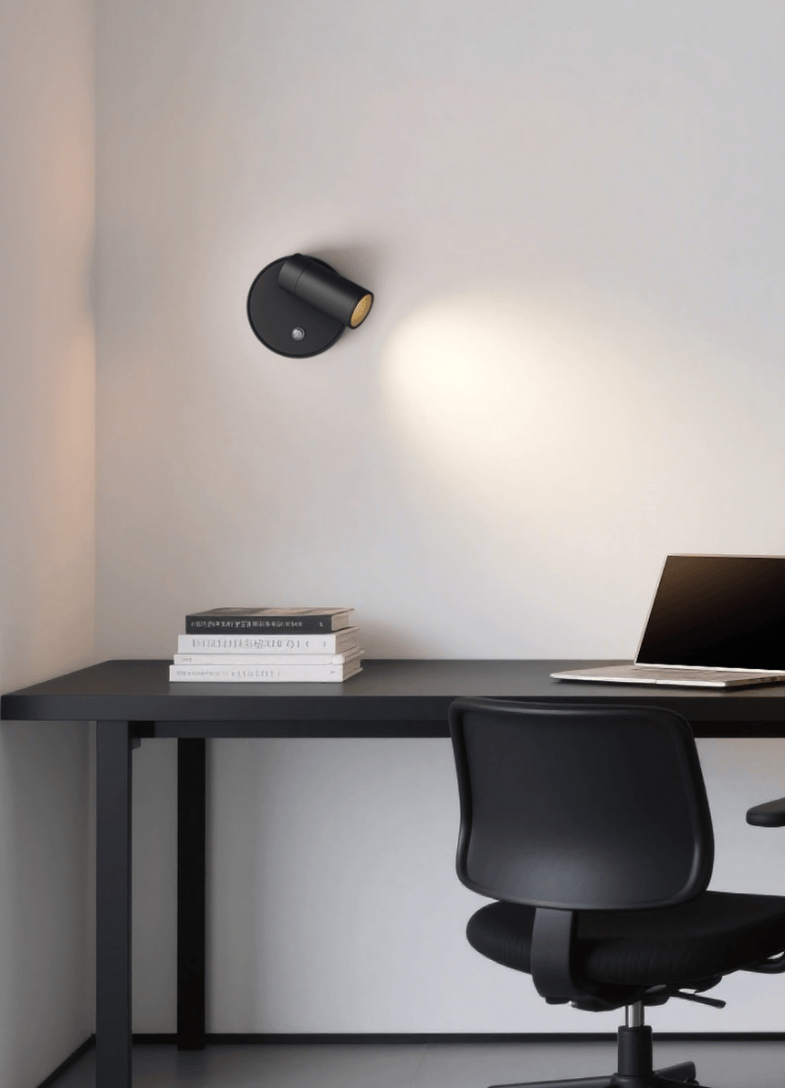 Lit above a dark desk and office chair, the beam grazing the wall downward