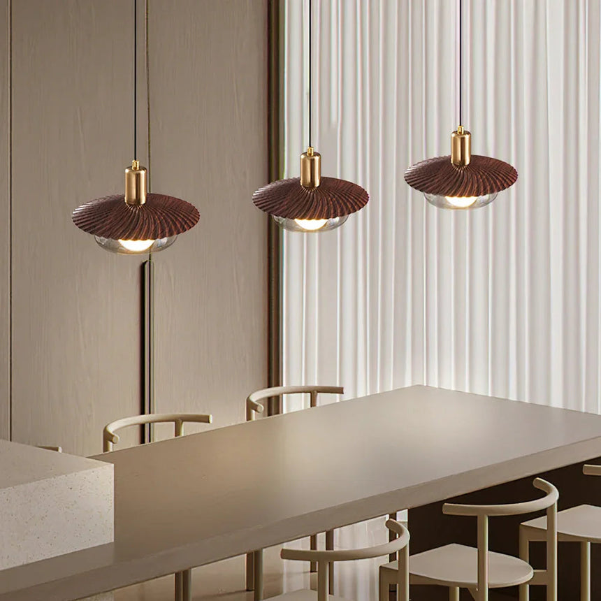 Three walnut grain discs lit above a long table in a bright office