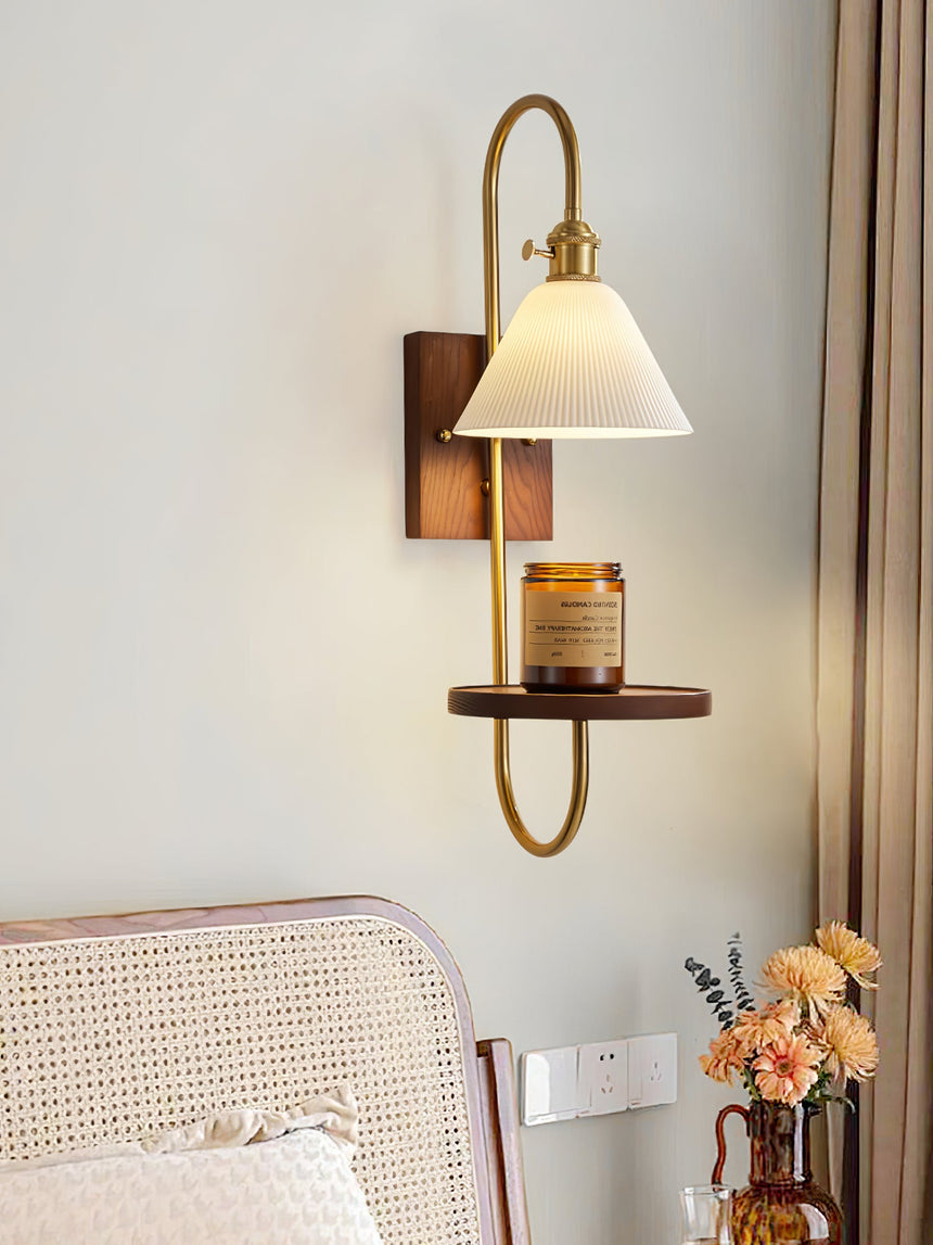 Sconce lit in a bedroom above a cane bed and a vase of flowers