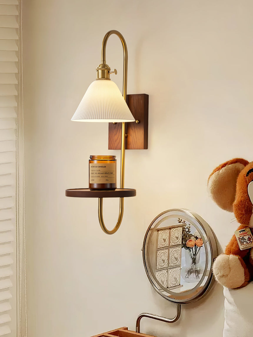 Sconce lit above a dresser beside a round mirror and small objects