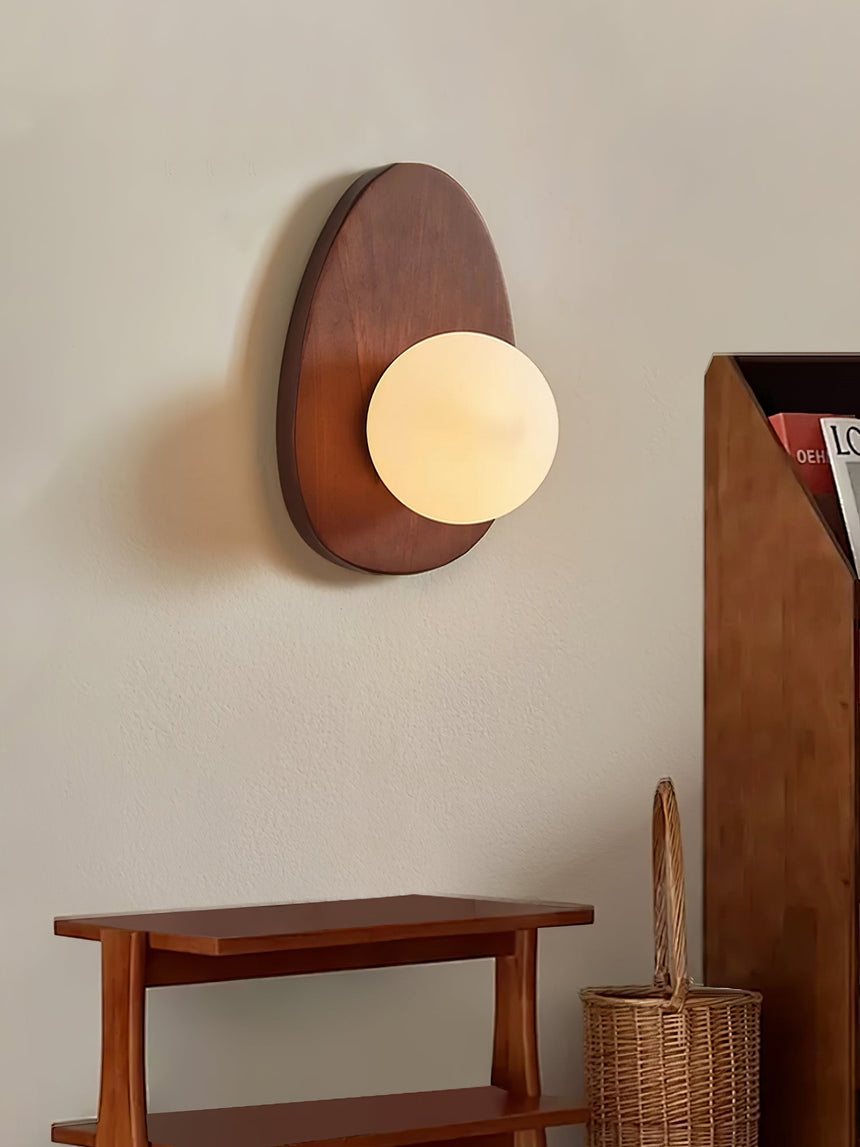 Sconce lit above a low wood bench beside a woven basket on the floor