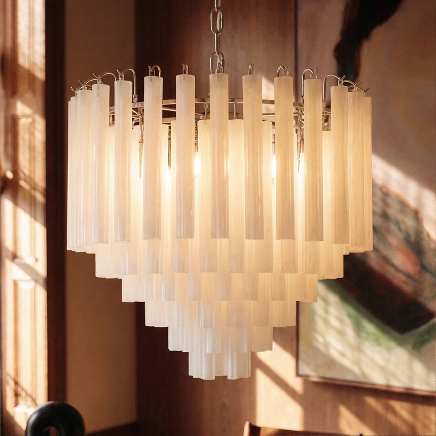 The frosted tubes lit close beside a large framed painting on a brown wall