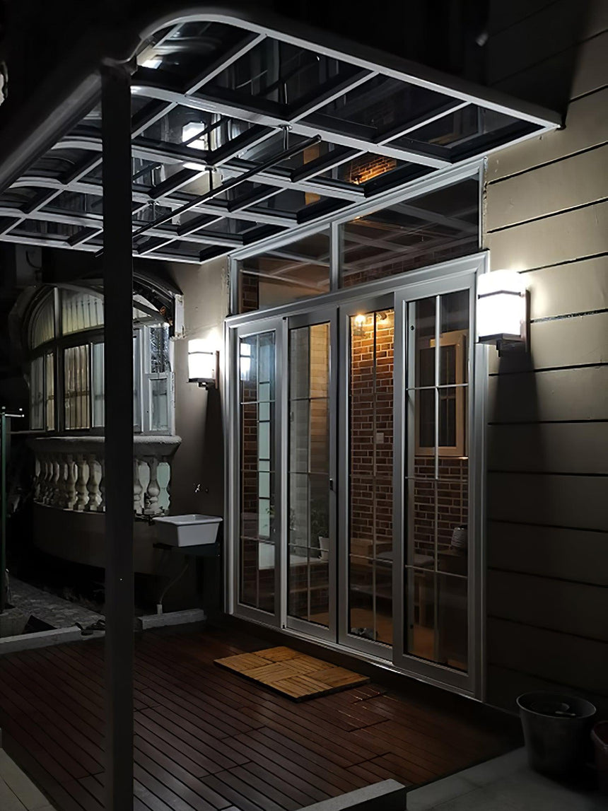 The light lit on dark cladding beside a glass door onto a covered deck at night