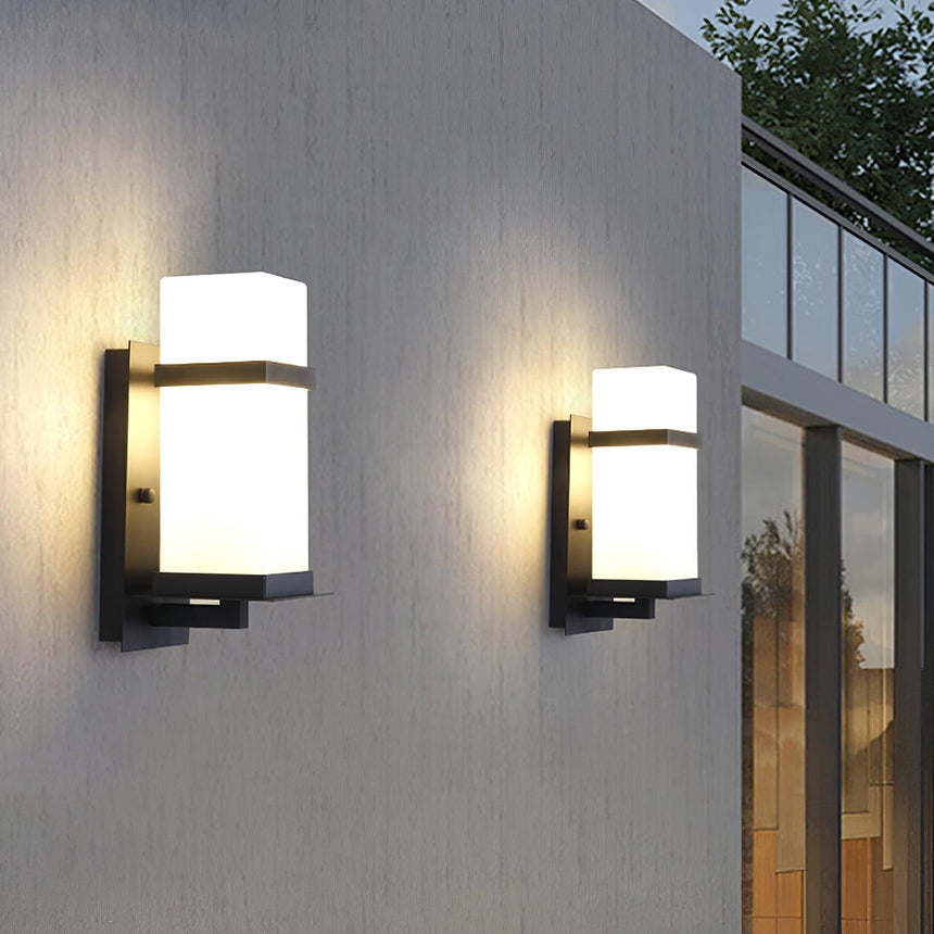 Two lights lit on a gray facade beside a tall window