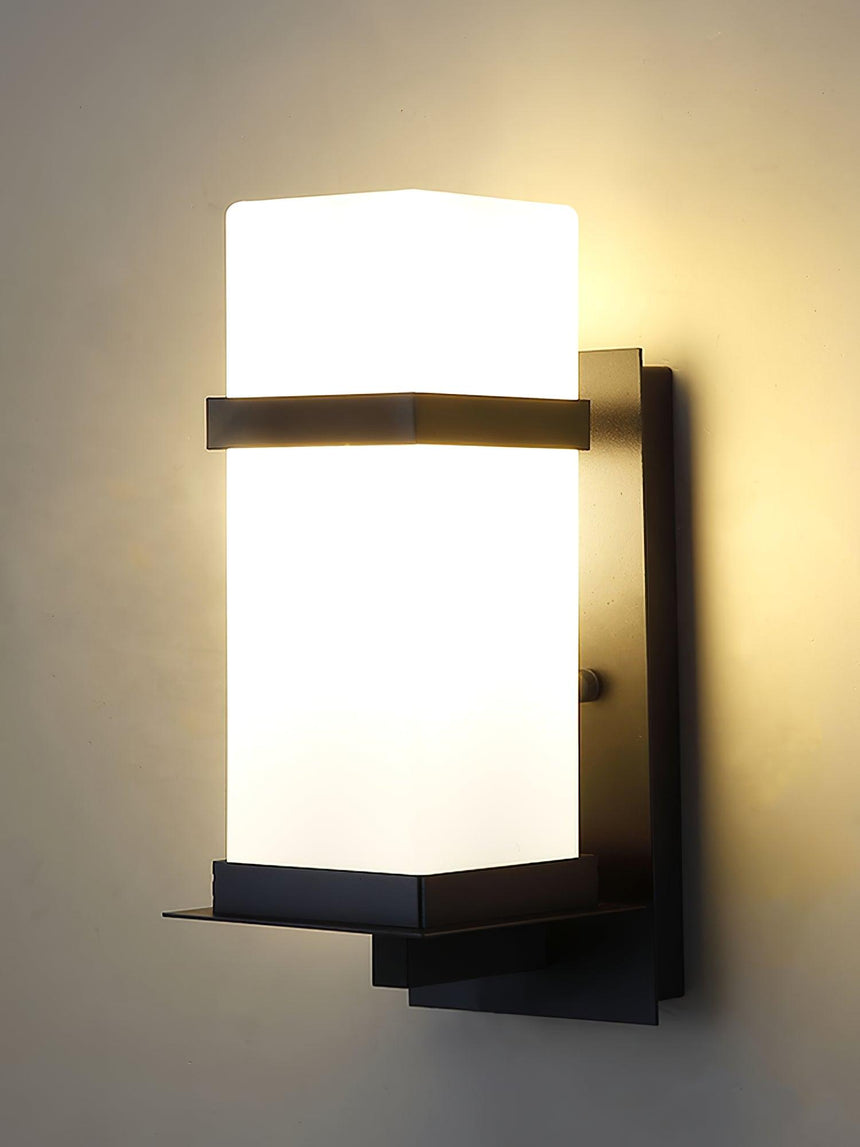 The glass cube lit warm on a beige wall, the black band across its upper part