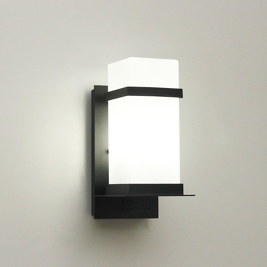 The light unlit on a pale wall, the white glass and the black frame