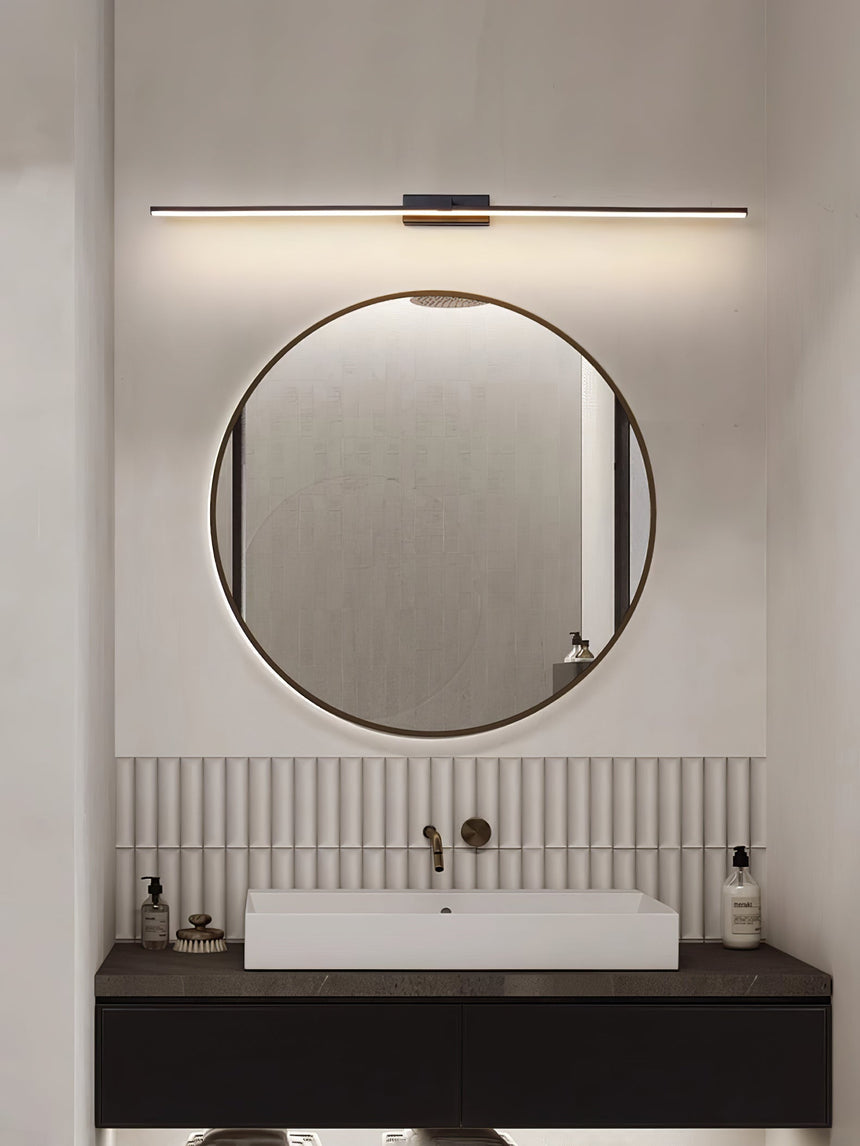 Bar lit above a round mirror over a stone basin on a dark timber vanity