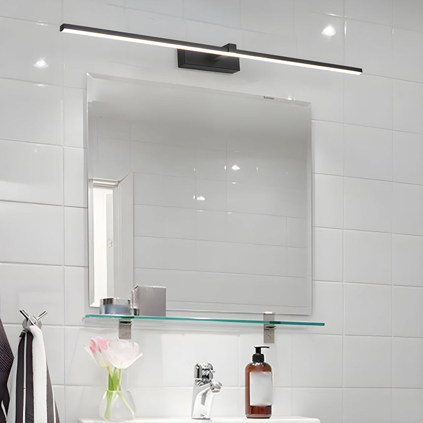 Bar lit above a square mirror in a white tiled bathroom with a glass shelf