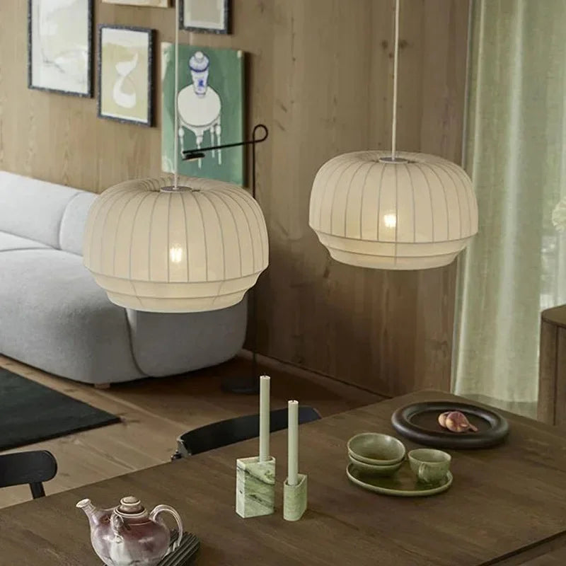 Two knitted cloth shades lit above a low table in a wood lined room