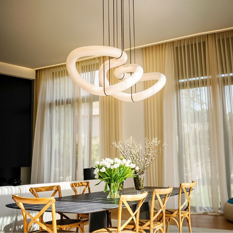 The lit ribbon above a dining table with chairs, flowers and long curtains
