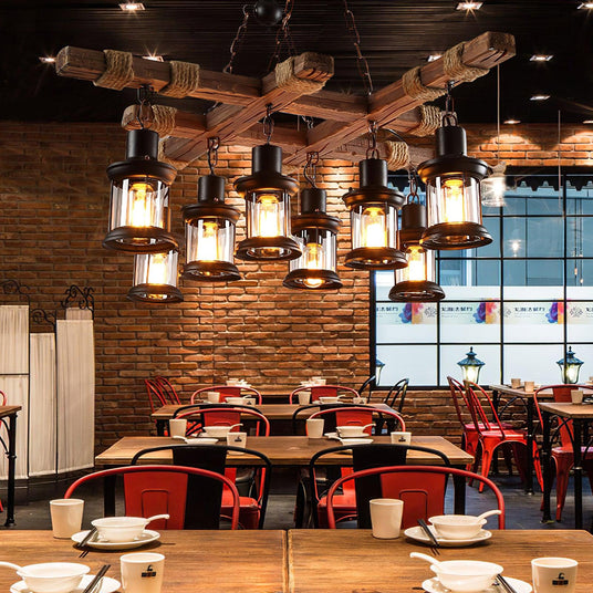 Hung over red chairs and wood tables in a room with a brick wall and windows