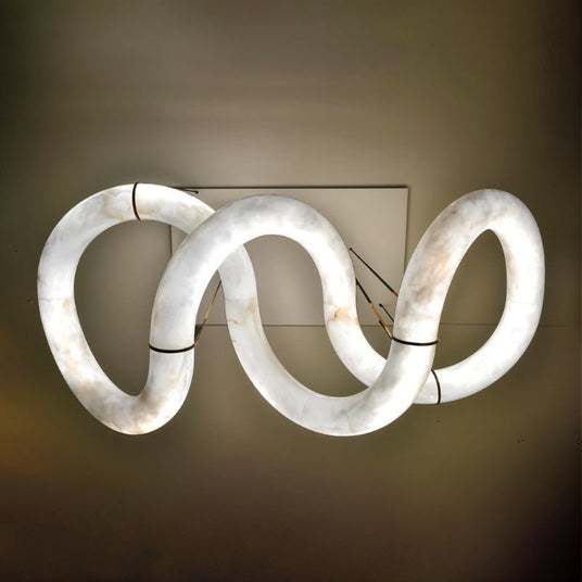 The winding ribbon lit against a dark ground, the loops of stone clearly visible