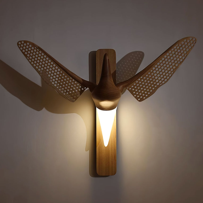 The white diffuser lit warm between the wings on a dark wall