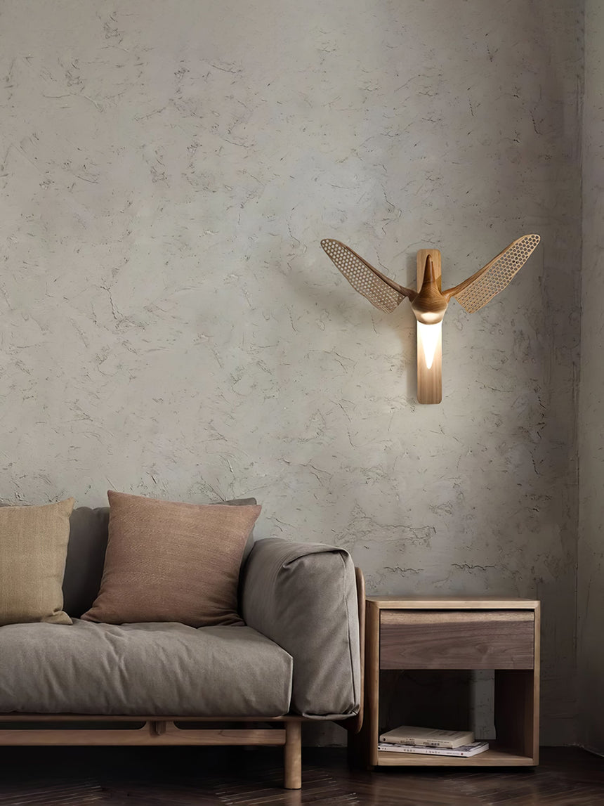 Sconce lit above a sofa with cushions beside a small dark side table