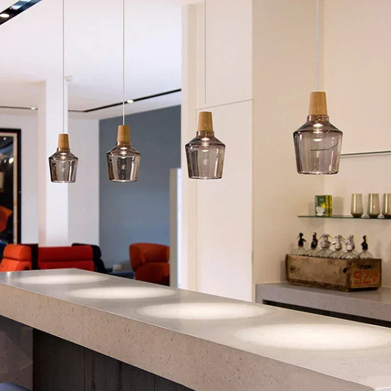 Three pendants lit in a row above a pale kitchen bar counter