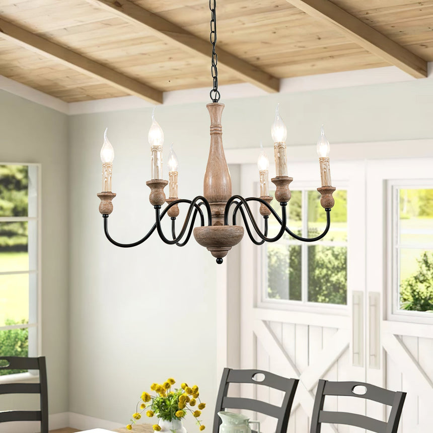 Lit above a dining table and dark chairs in a room with a beamed ceiling and windows