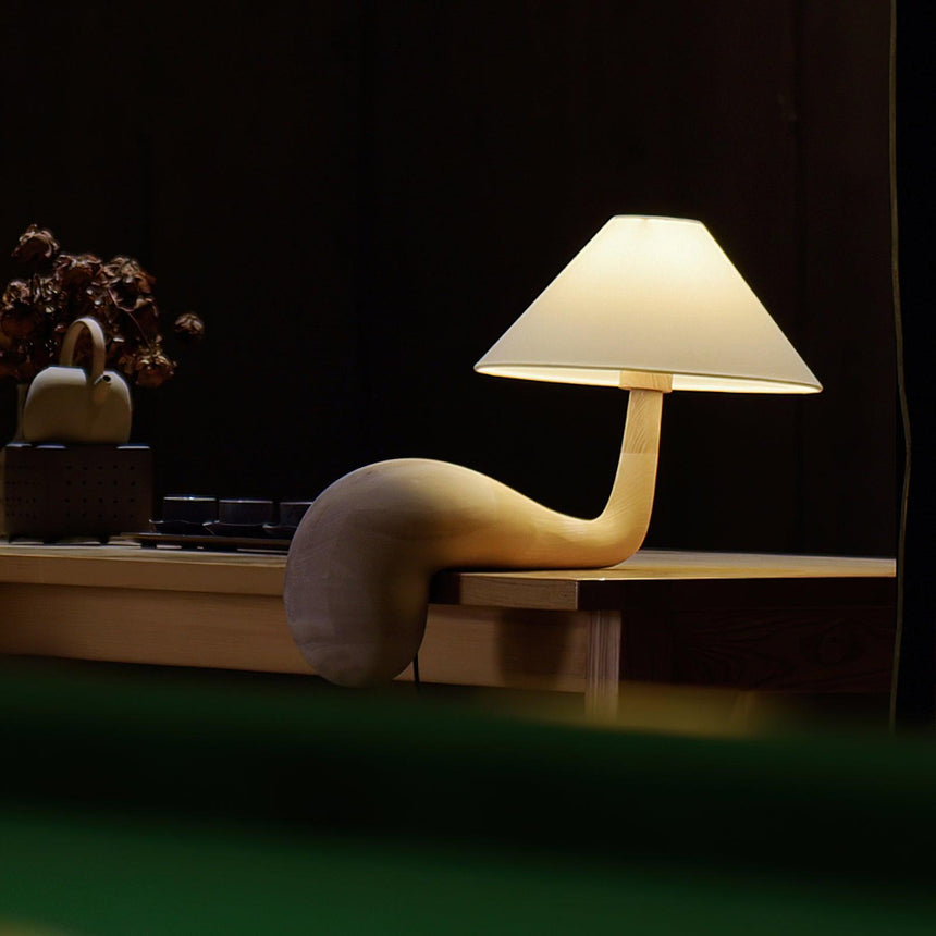 Wood desk lamp lit in a dark room on a low wooden surface
