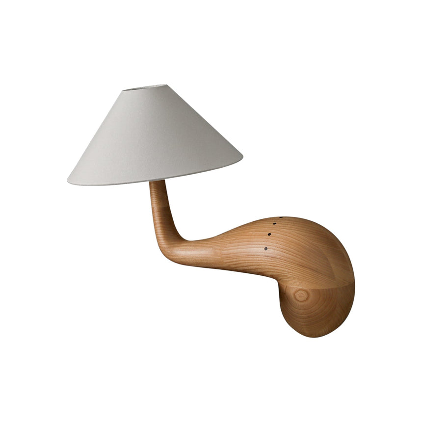 Natural wood desk lamp seen from the side against a plain ground