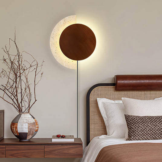 Plug in sconce lit above a nightstand beside a bed with a leather rail