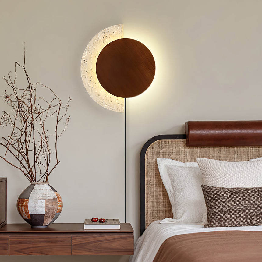Plug in sconce lit above a nightstand beside a bed with a leather rail