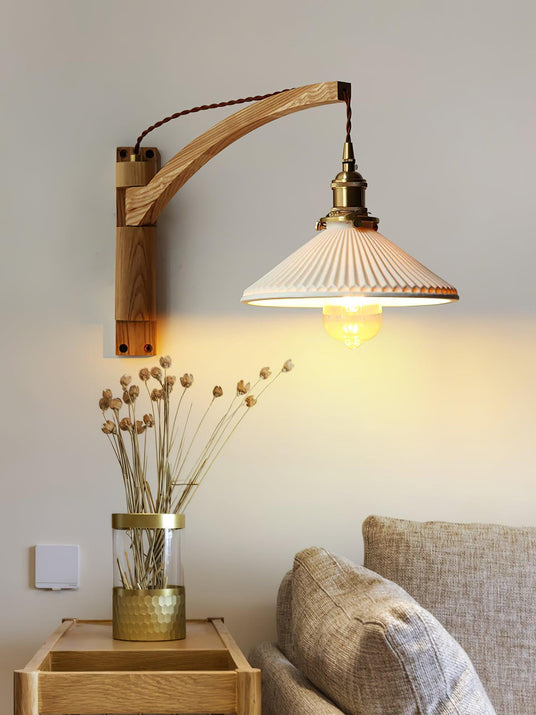 The light lit above a small table with dried flowers beside a gray sofa