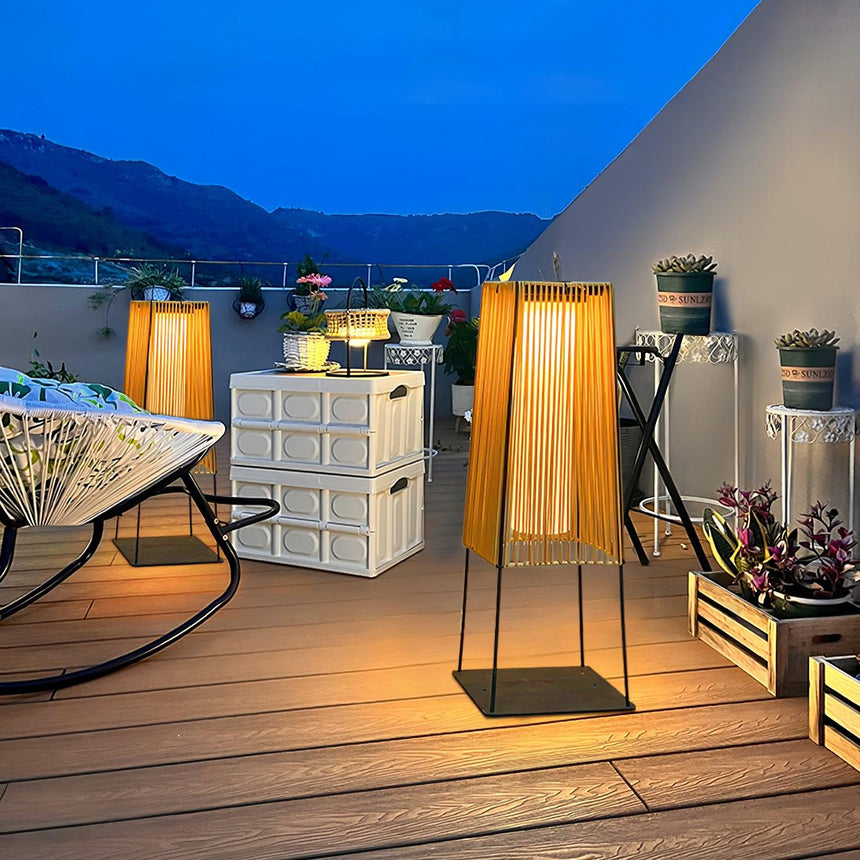 Two lit on a roof terrace at dusk beside planters and a low bench