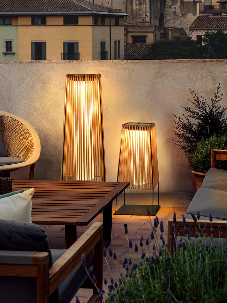 Two lit on a terrace beside a timber table and a woven armchair