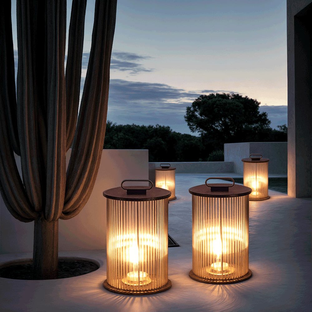 Ribbed glass outdoor lantern light with warm LED glow placed along a modern garden wall at night