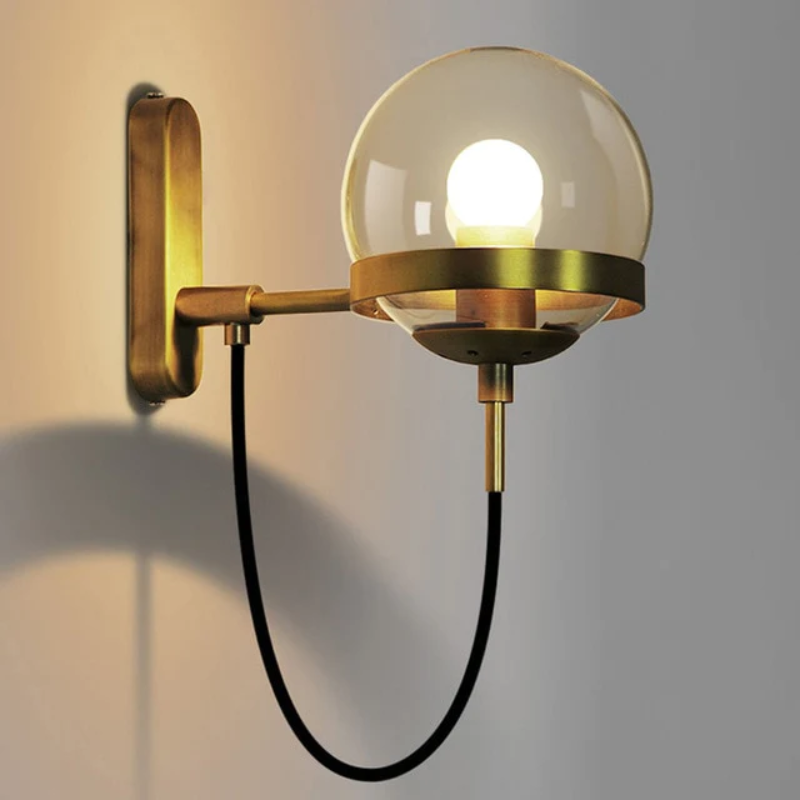 Glass globe wall sconce with black metal ring and bronze accents mounted in an industrial glam living room