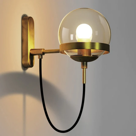 Glass globe wall sconce with black metal ring and bronze accents mounted in an industrial glam living room