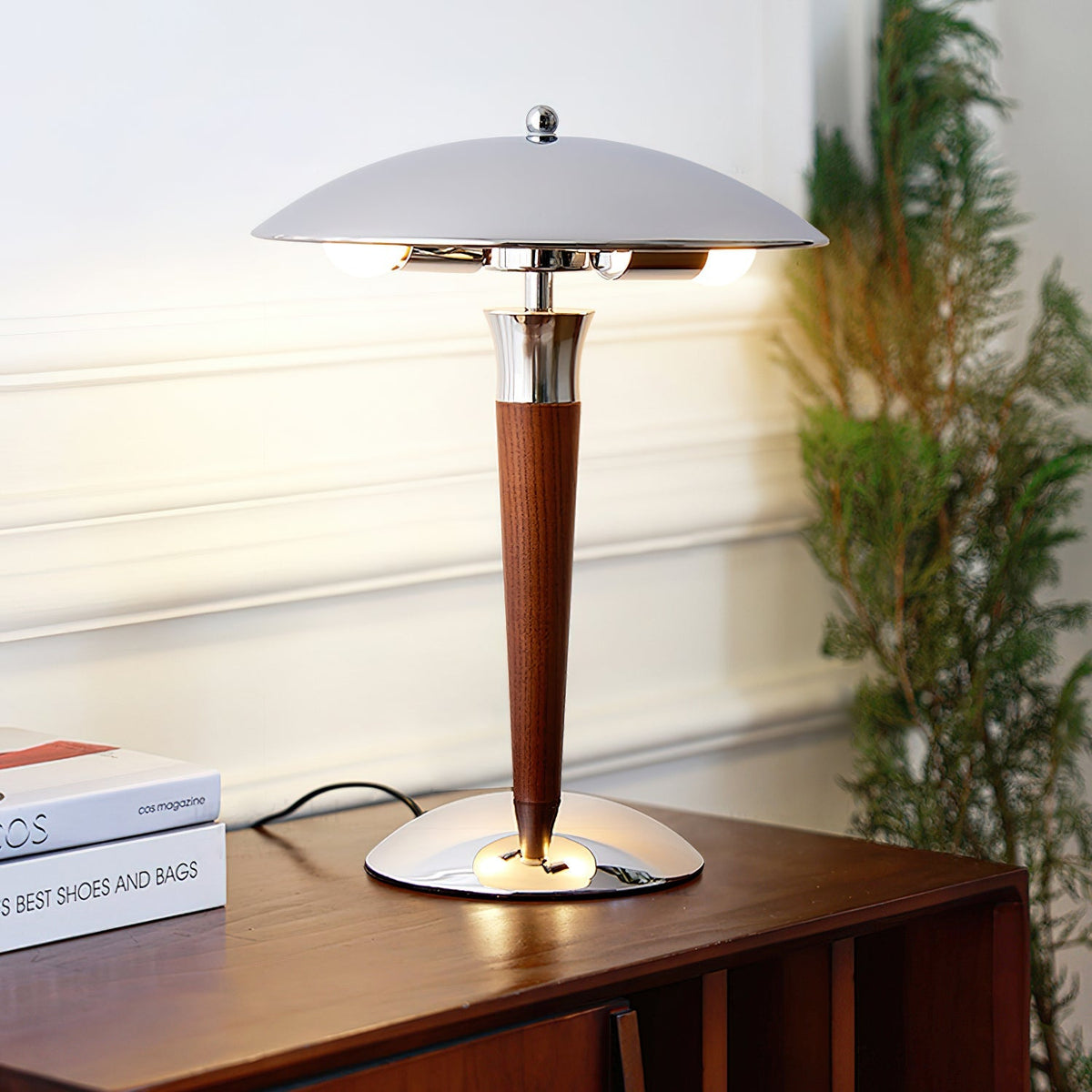 Mid century modern table lamp with a chrome dome lit on a wood console