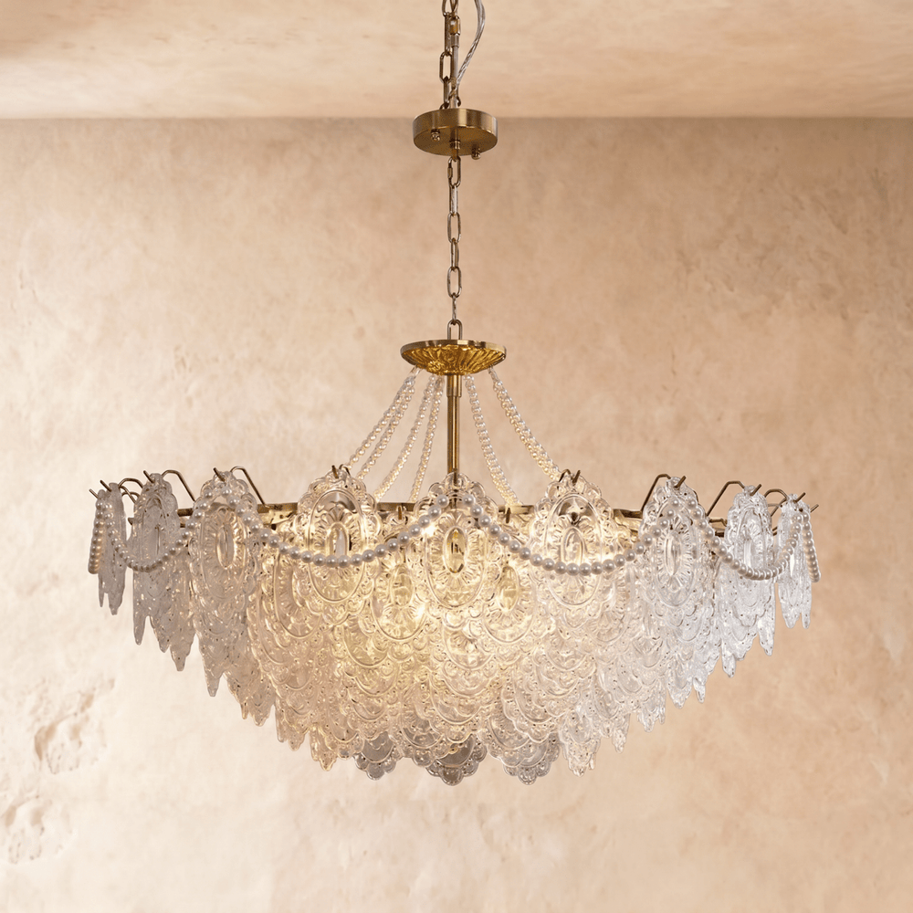 A brass framed chandelier with tiers of pressed clear glass petals lit inside