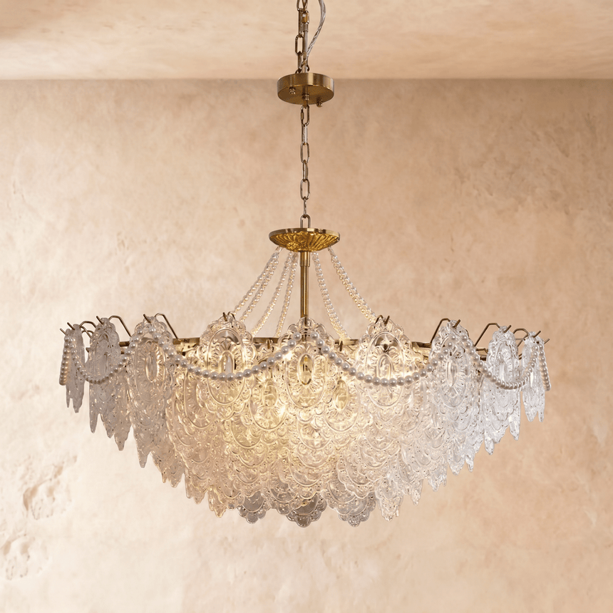 A brass framed chandelier with tiers of pressed clear glass petals lit inside
