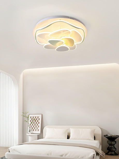 Cloud motif ceiling light lit above a bed with a quilted headboard