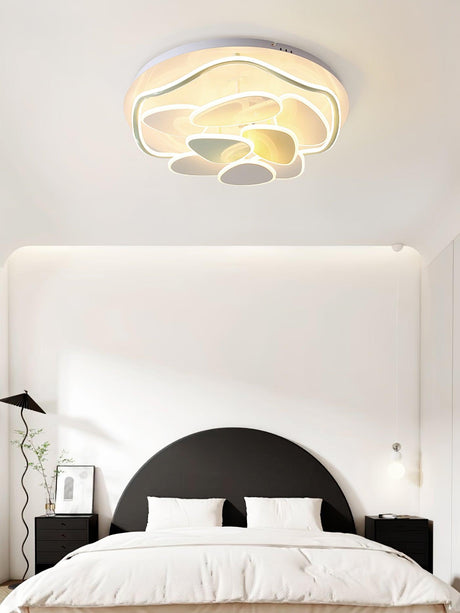 Cloud motif ceiling light above a bed with a dark arched headboard