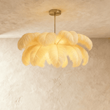A dome of white ostrich feathers lit from within, hung from a slim gold stem