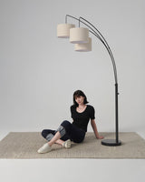 Black three arm lamp on the same woven rug with a seated figure below