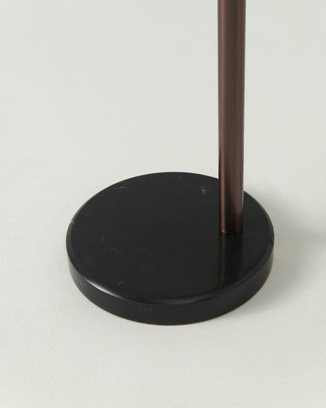 The bronze pole set into a low round black base on a pale floor
